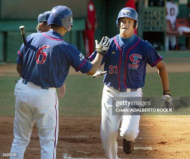 Taiwan's Lin Chih-Sheng is greeted by teammates after completing the first run during the Taiwan-USA game at the XXXV Baseball World Cup, 22 October...