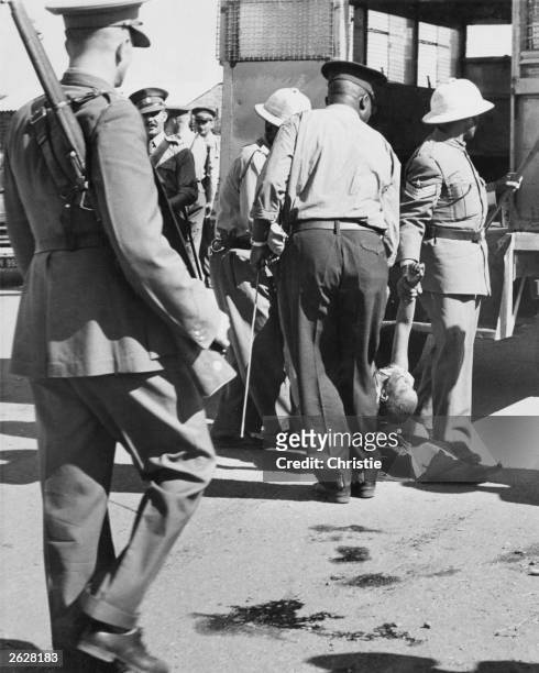 South African police take away the body of a black woman killed during the Sharpeville massacre. Police opened fire on a crowd protesting against...