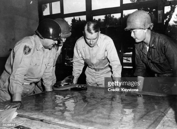 United States Army Chief of Staff General Collins studying a map of the front line during the battle for Korea, with Lieutenant General Walker,...