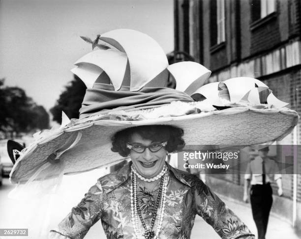 Australian comedian Barry Humphries, dressed as his most famous character Dame Edna Everage, modelling a stunning Ascot hat based on the Sydney Opera...