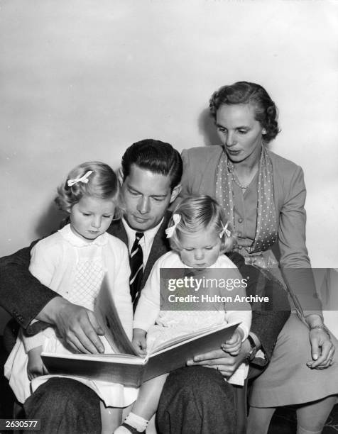 Michael, King of Romania with his wife, Princess Anne and his daughters, Princess Helen and Princess Margaret. He is reading a bedtime story.