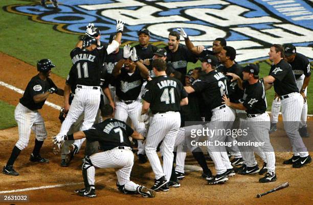 Alex Gonzalexz of the Florida Marlins leaps into the arms of his teammates at home plate after hitting a walk off solo home run to win the game in...