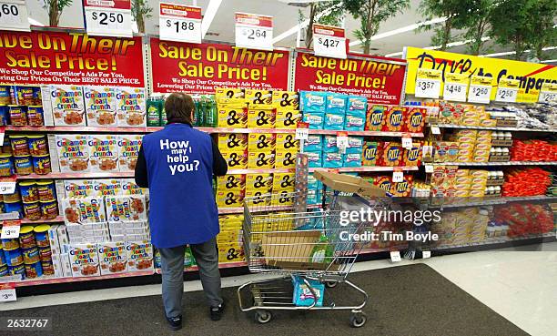 Wal-Mart worker Bella Battista, wearing her "How may I help you?" vest, stocks shelves November 13, 2002 at a Wal-Mart store in Mount Prospect,...