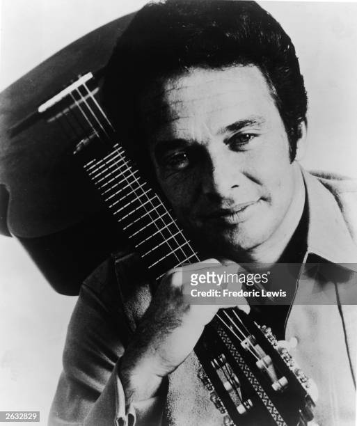 Promotional studio portrait of American country singer and songwriter Merle Haggard holding an acoustic guitar, circa 1970.