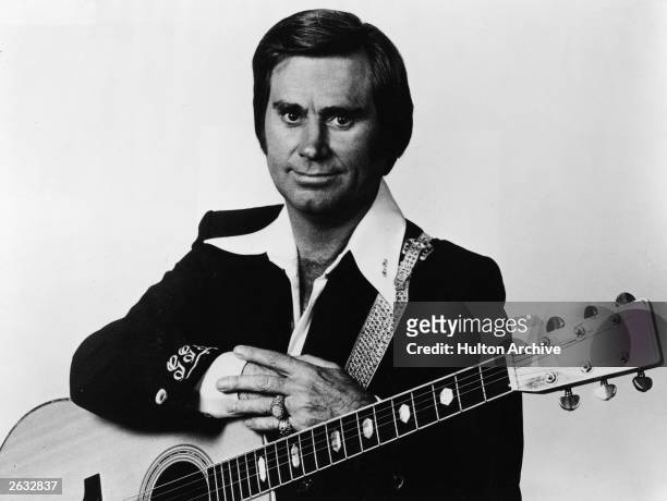 Promotional studio portrait of American country singer and songwriter George Jones with an acoustic guitar, circa 1970.