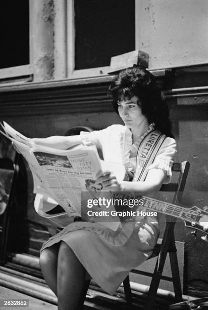 American country singer and songwriter Loretta Lynn reads a newspaper backstage at the Grand Ole Opry, Nashville, Tennessee, early 1960s.