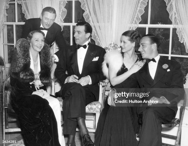 Canadian actor Walter Pidgeon , centre, attends a dinner party at the home of Raul Walsh, the other guests with him are, from left to right, Rita...