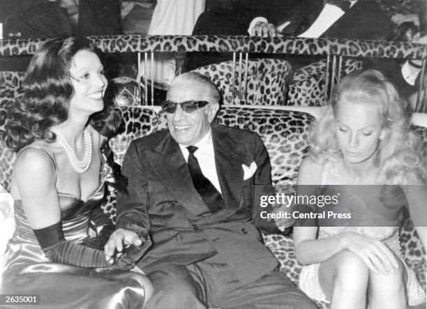 Aristotle Onassis wears his trademark 'shades' while partying with Elsa Martinelli in Paris.