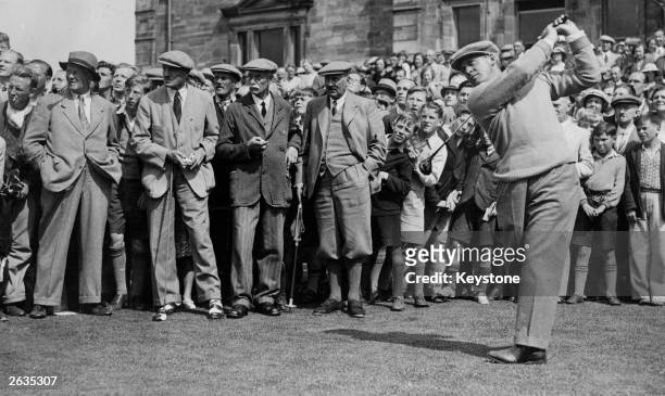American golfer Bobby Jones driving off at St Andrews while a large crowd of admirers gathers behind him. Jones won the British Open three times and...