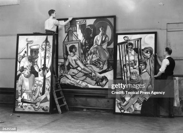 Two men prepare to hang German Expressionist painter Max Beckmann's triptych 'Temptation' at the 20th Century German Art Exhibition at the New...