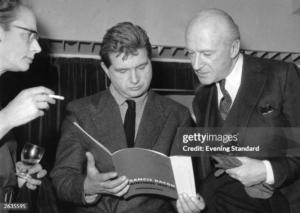 Irish painter Francis Bacon , reading his exhibition catalogue, and English photographer Cecil Beaton at the Marlborough Gallery, London.