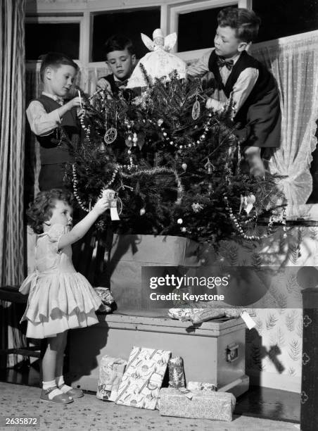 Four young children decorating their Christmas tree at home in Ilford, Essex.
