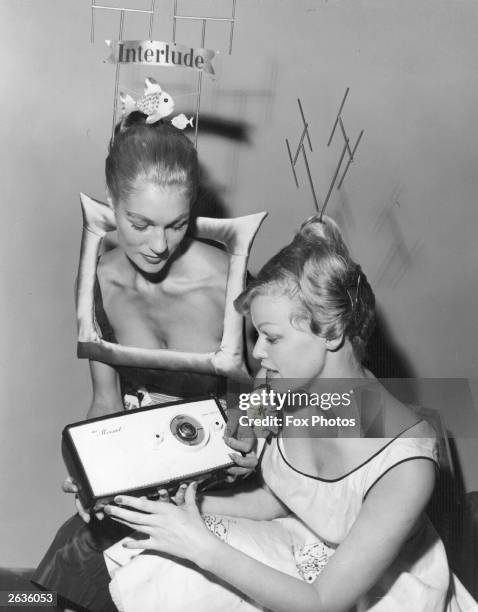 Model Heather Wyatt , dressed as a television set, shows Eva Brann, Miss Sweden 1957, the Minuet Pains Portable Radio at the National Radio Show at...