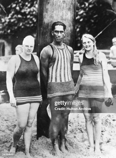 Duke Kahanamoku Hawaiian swimmer and surfer with Charlotte Boyle and Ethelda Bleibtrey, practicing on a beach in Waikiki for the 100 yards National...