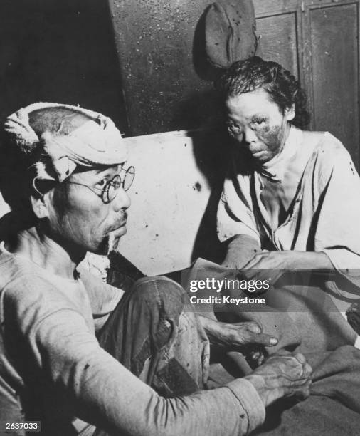 Victims of the atomic bomb attack of 6th August sit in a makeshift hospital in a damaged bank building in the centre of Hiroshima, 5th October 1945.