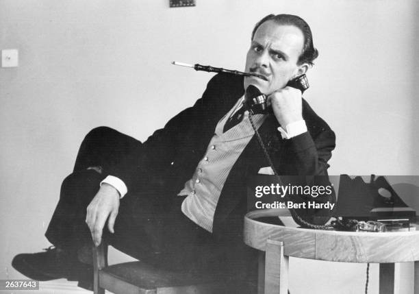 Terry-Thomas , British television and film actor, making a telephone call. Original Publication: Picture Post - 7292 - When A Man Is Kept Late At The...