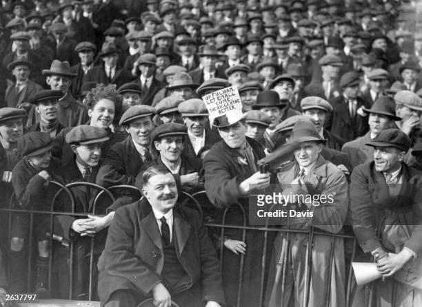 The football crowd at Fulham's Craven Cottage stadium in one of the final rounds of the F A Cup competition. The sign on one fans hat reads 'Up...