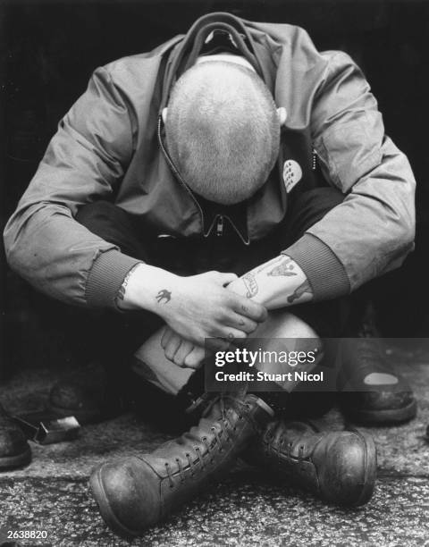 Skinhead sitting cross-legged during a British Movement rally in Notting Hill, London.