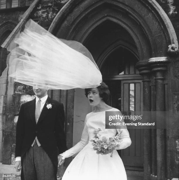 The veil of newly-wed bride Eileen Petticrew flies up in a gust of wind as she poses for photographs with husband Robert Greenhill outside St John...