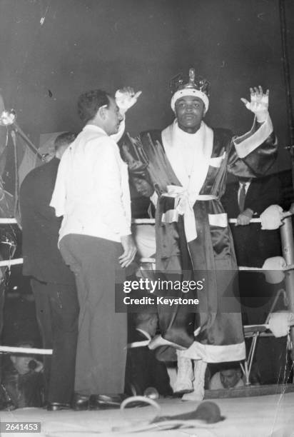 Before his fight with British boxer Henry Cooper at Wembley Stadium, American boxer Cassius Clay parades in the ring before the crowd of 55,000...