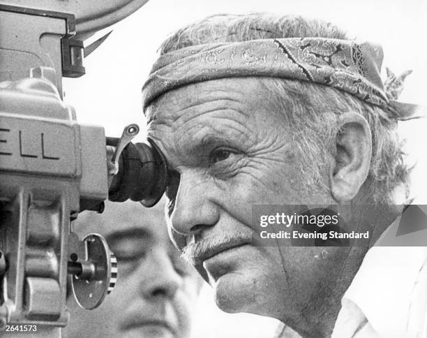 American film director Sam Peckinpah looking through the camera lens whilst filming 'Cross of Iron'.