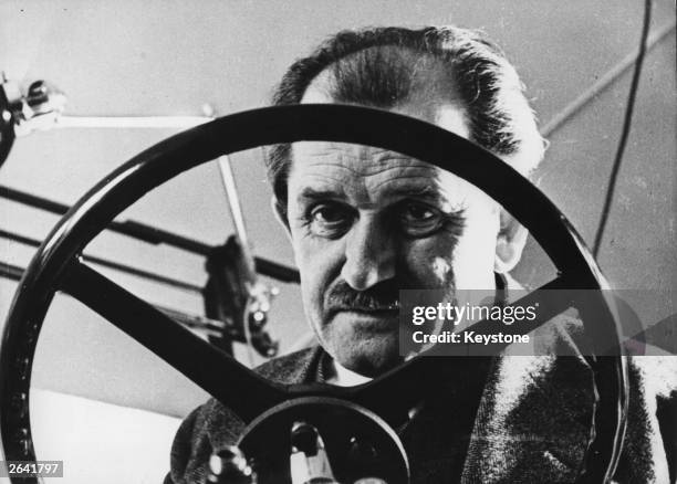 Automotive engineer Ferdinand Porsche , the designer of the Volkswagen Beetle, behind the wheel of one of his creations.