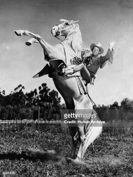American singing cowboy star Roy Rogers , born Leonard Slye riding his horse and longtime co-star Trigger .