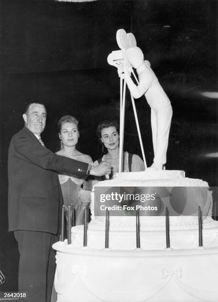 English film magnate Joseph Arthur Rank, , celebrates 21 years of Pinewood Studios, ; he cuts the birthday cake, watched by actresses Belinda Lee, ,...