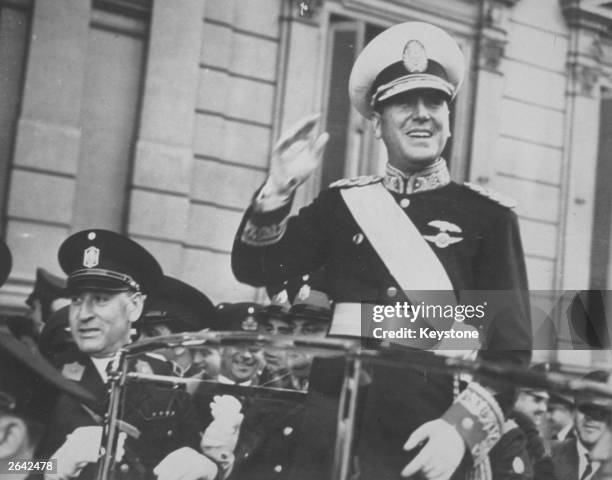 Juan D Peron, smiling from his car, as he travels along the Avenida de Mayo to Government House to assume the Presidency.
