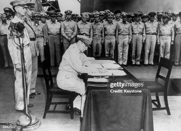 General MacArthur , signs the Japanese Instrument of Surrender on board the USS Missouri in Tokyo Bay, 2nd September 1945. Amongst those standing...