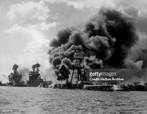The USS Arizona burning furiously in Pearl Harbour after the Japanese attack. To the left of her are USS Tennessee and the sunken USS West Virginia.