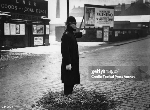 Policeman on point duty in Yorkshire, standing on a pile of straw to keep his feet warm.