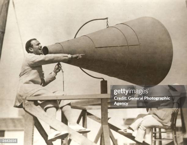 Douglas Fairbanks Snr using a giant megaphone during filming of the United Artists production 'The Gaucho'.