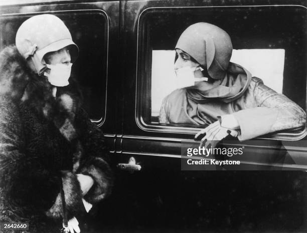 Two women wearing flu masks during a flu epidemic in 1929.