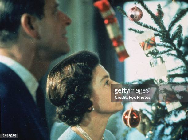 Queen Elizabeth II and Prince Philip look at their decorated Christmas tree during the filming of 'The Royal Family', a joint ITV-BBC television...