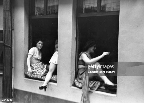 Licensed street prostitutes barter with customers through the windows of their brothels in Hamburg. Original Publication: Picture Post - 4854 - The...