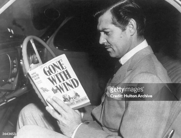 American film star Clark Gable reading the novel 'Gone With the Wind' by Margaret Mitchell. His greatest role was that of Rhett Butler in the MGM...