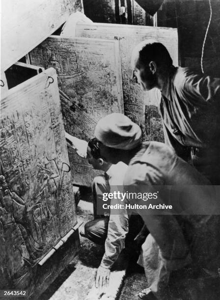 British archaeologist and Egyptologist Howard Carter , an Egyptian team member and his Arthur Callender in the burial chamber, looking through the...