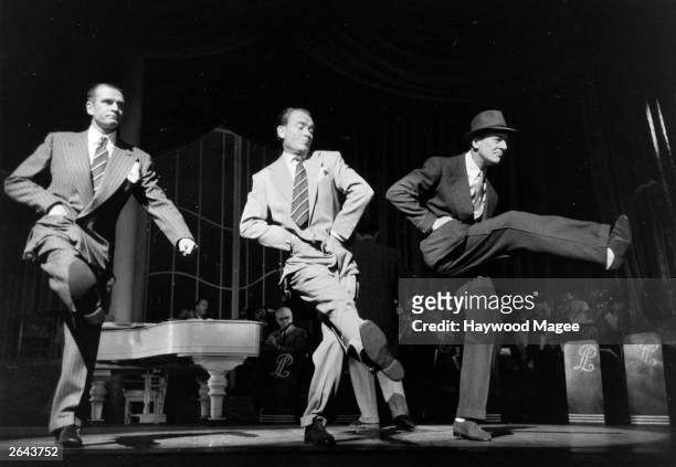 Actors Laurence Olivier, John Mills and John Gielgud dancing on stage at the London Palladium. Original Publication: Picture Post - 6554 - Midnight...