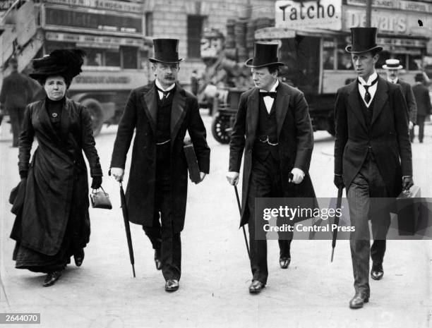Winston Churchill listens attentively to David Lloyd George, Chancellor of the Exchequer, while walking in Central London with him, his wife and his...