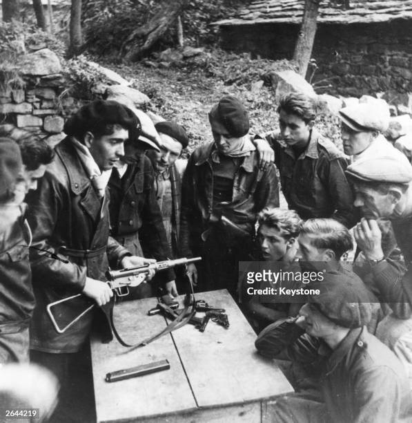Members of the Maquis, the French Resistance, study the mechanism and maintenance of weapons dropped by parachute in the Haute Loire. They include a...