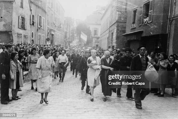 Woman, with her baby whose father is German, and her mother are jeered and humiliated by crowds in Chartres after having their heads shaved as...
