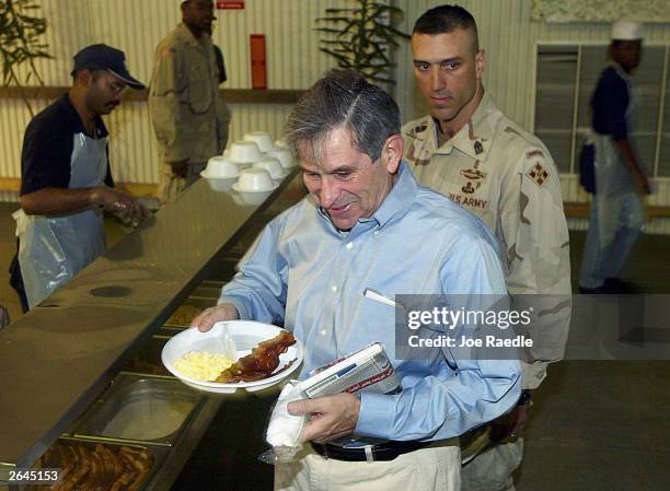 Deputy Defense Secretary Paul Wolfowitz carries his breakfast as he visits the American 4th Infantry Division base October 25, 2003 in Tikrit, Iraq....