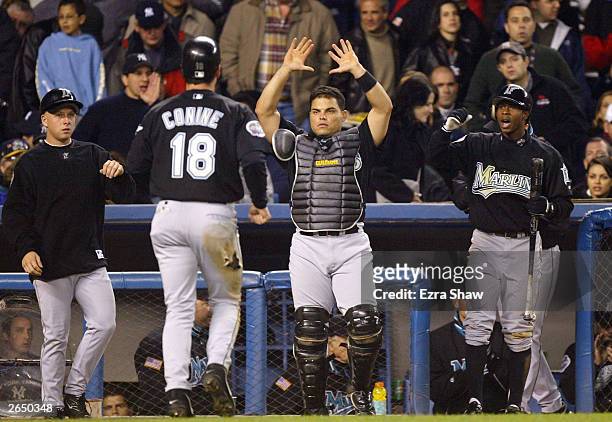 Jeff Conine of the Florida Marlins is congratulated by his Ivan Rodriguez and Juan Pierre after scoring on a sacrifice fly by teammate Juan...