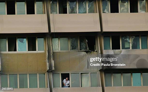 Man looks out of his window at the damaged windows and balconies at the Al Rasheed Hotel after at least six rockets were fired at the building...