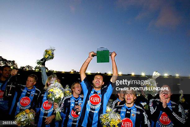 Dutch Geert den Ouden of Djurgaarden holds the trophy while celebrating the team's victory in the Swedish national league 26 October 2003, in...