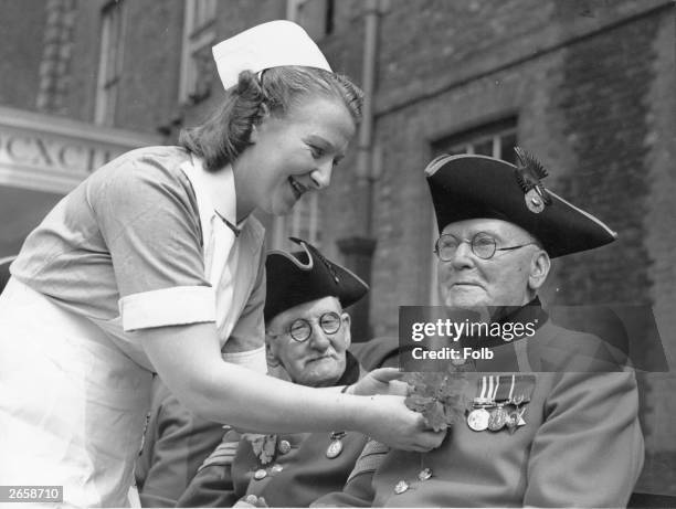 An oak leaf being pinned on Sargent Joseph Jones, of the 19th Hussars, the oldest Chelsea pensioner taking part in the Founders Day Parade. The...