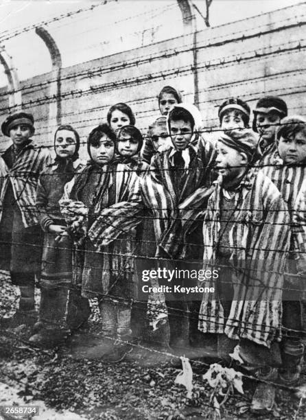 Group of child survivors behind a barbed wire fence at the Nazi concentration camp at Auschwitz-Birkenau in southern Poland, on the day of the camp’s...