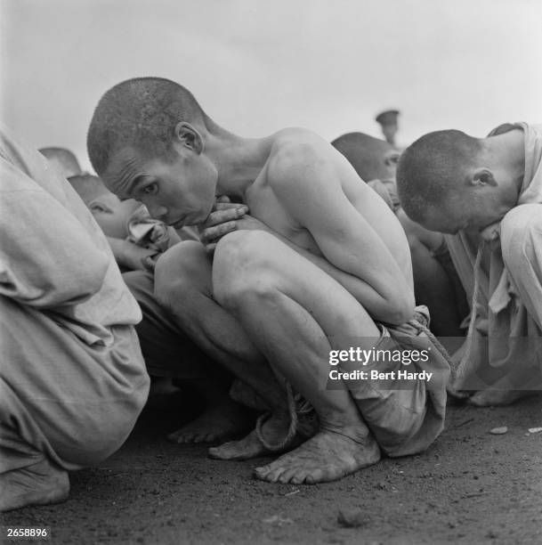 Line of South Korean prisoners crouching on the ground, 1950. They are political prisoners, arrested for their alleged sympathies with the communist...