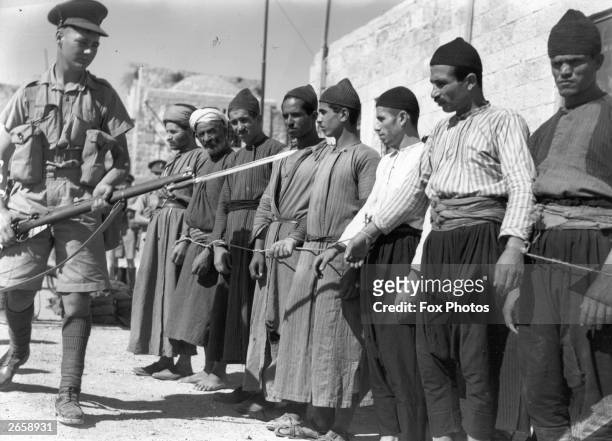 Group of Arab prisoners in the Old City of Jerusalem is guarded by a soldier armed with a rifle and bayonet.
